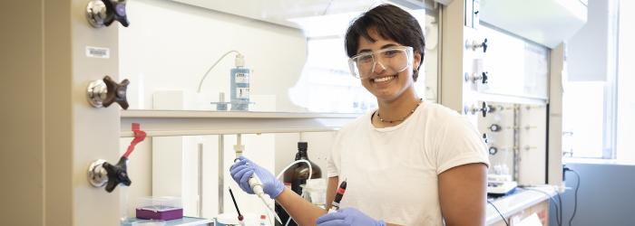 student smiles holding a pipette
